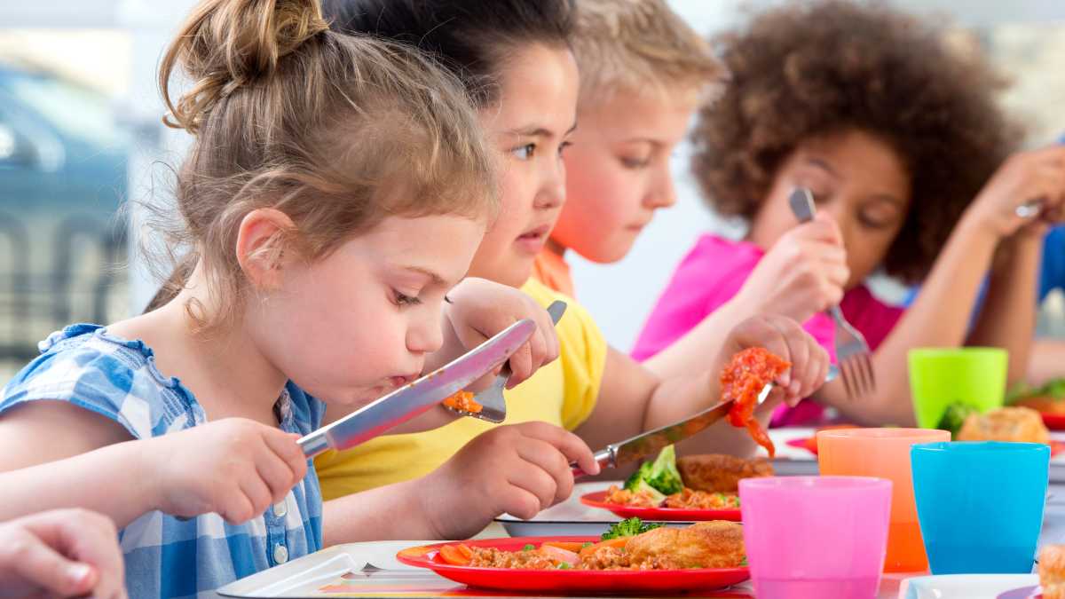 Niños comiendo en comedor escolar incluyendo frijoles, superalimento recomendado por pediatra de Harvard