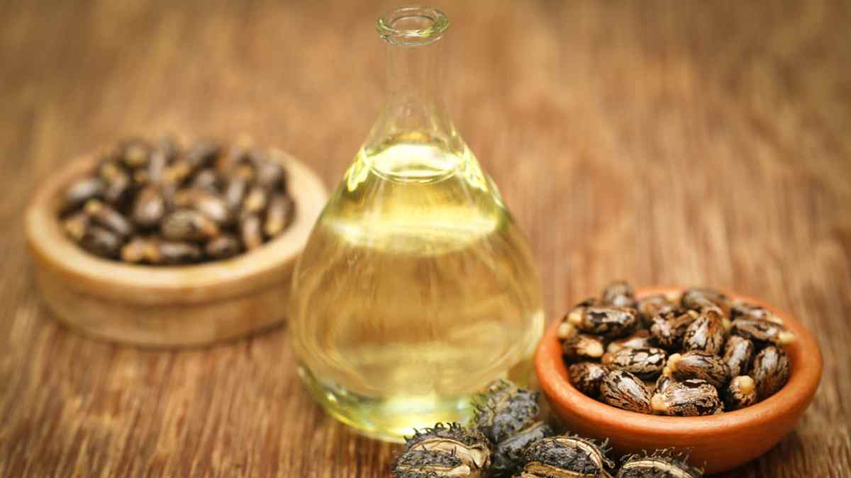 Botella de aceite de ricino con semillas en cuencos de madera para aliviar la hinchazón abdominal de forma tradicional.