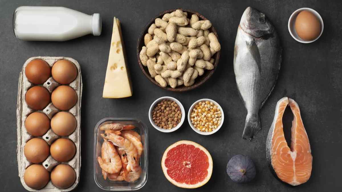 alimentos ricos en proteína: huevos, leche, queso, cacahuetes, pescado, salmón y camarones sobre fondo oscuro.
