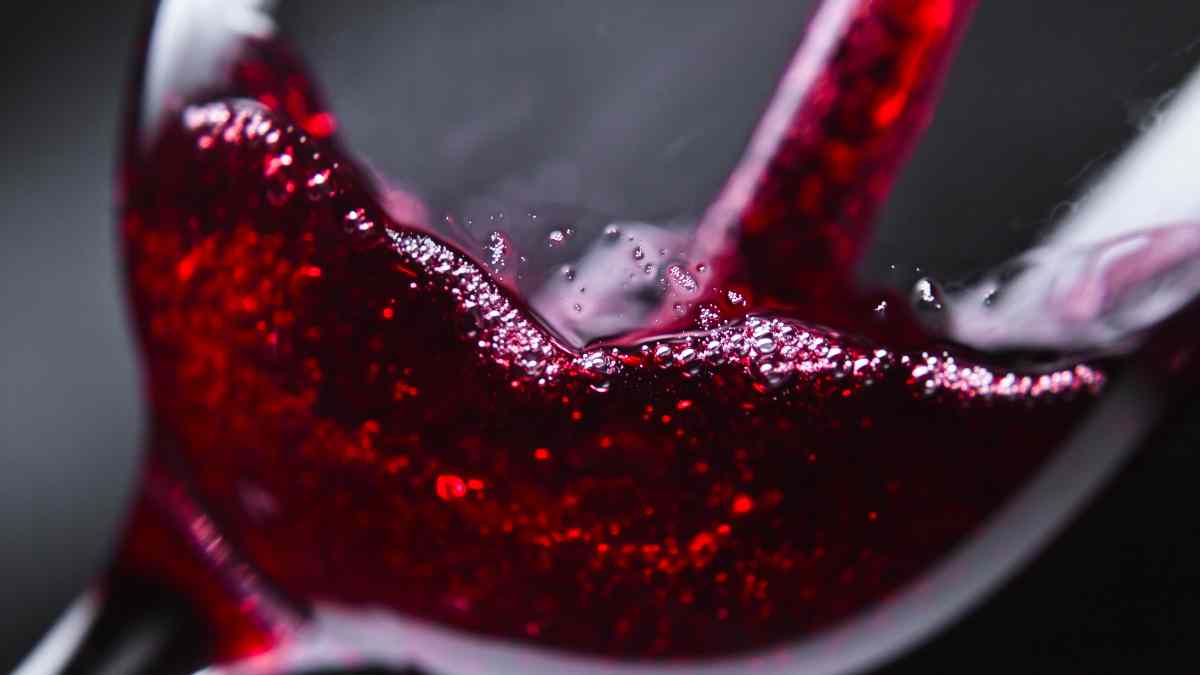 Copa de vino tinto siendo servida, ilustrando los efectos diarios del vino en la salud según la ciencia.