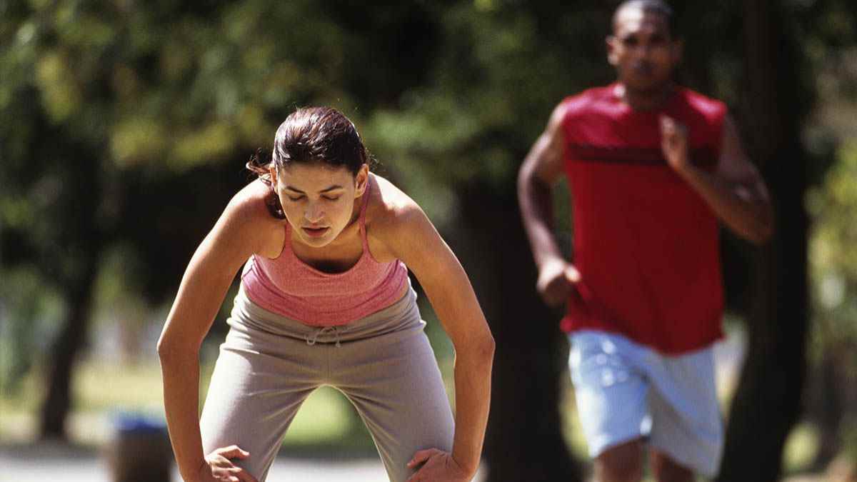 Mujer deteniéndose exhausta tras correr mientras su hermano la alcanza, ilustrando cómo cada cuerpo quema calorías y suda de forma diferente durante el mismo ejercicio.