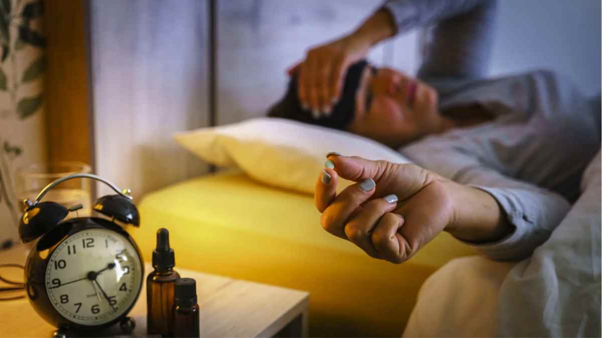 Mujer con insomnio sosteniendo una pastilla y mirando el despertador, símbolo de que acostarse tarde afecta la salud.