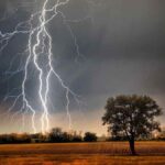 rayo impactando en un campo antes de llegar al suelo durante una tormenta.