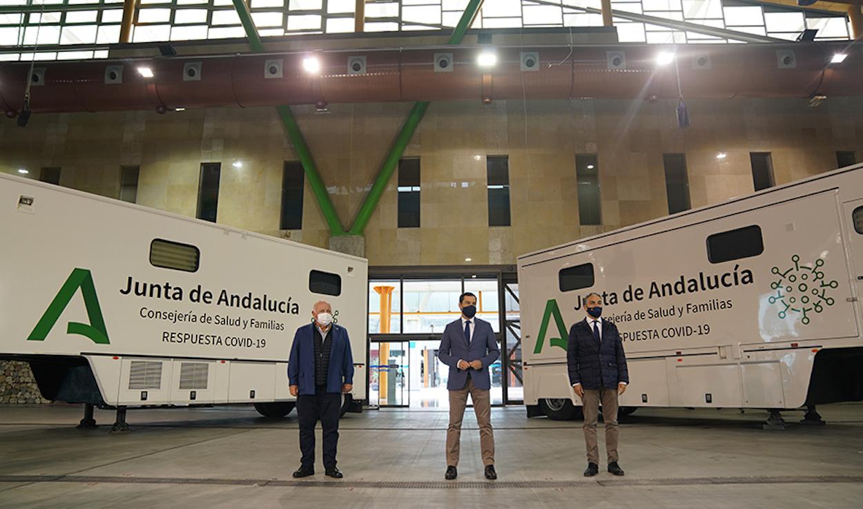 El presidente de la Junta, entre el consejero de Salud y el consejero de la Presidencia, ante dos de los vehículos.