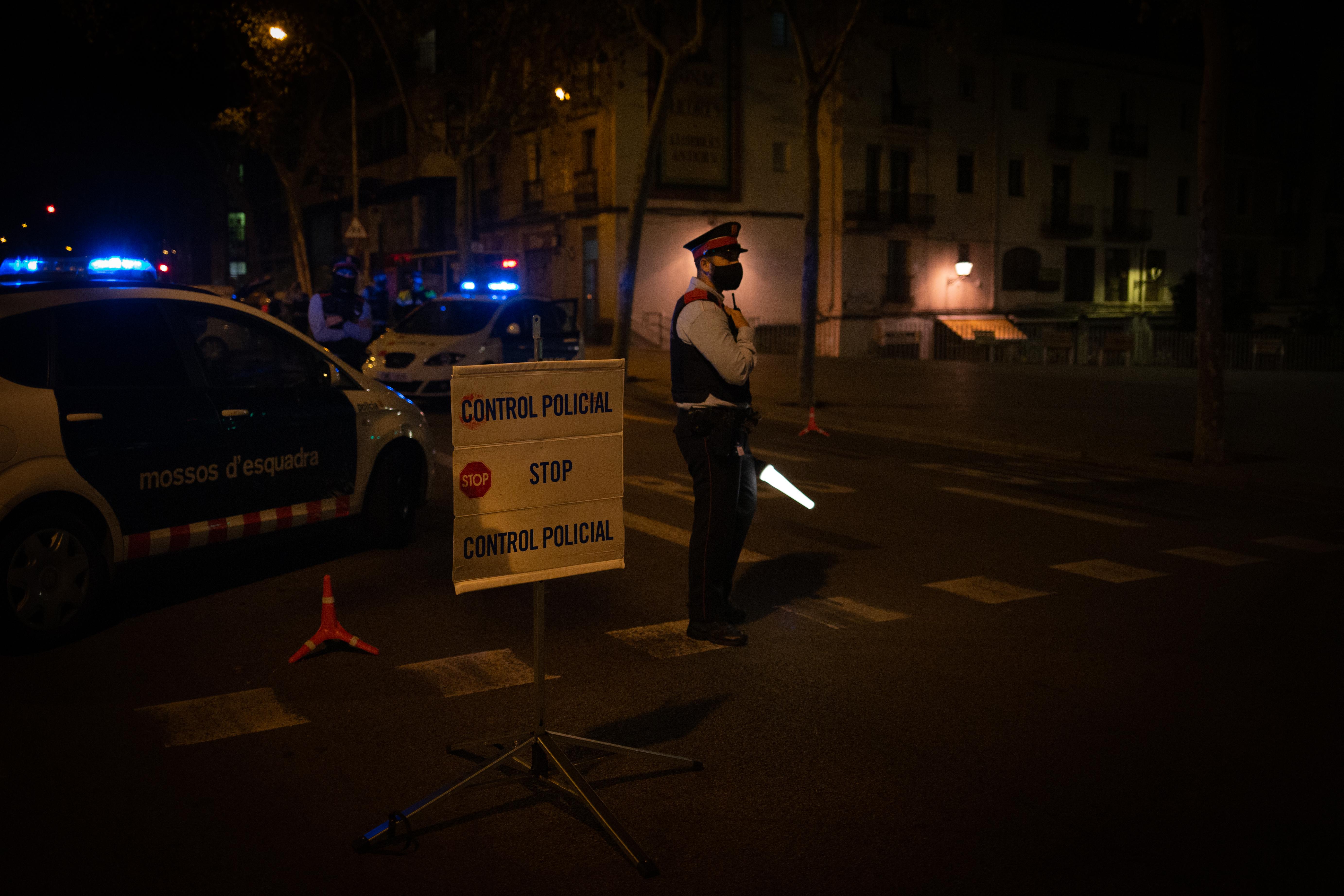 Un mosso d'Esquadra colabora en un control durante el toque de queda impuesto por la crisis sanitaria del Covid-19 desde las 22.00 horas a las 6.00 del día siguiente, en Barcelona