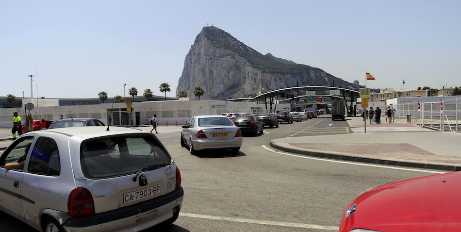 Coches hacen cola para entrar desde La Línea de la Concepción (Cádiz) a Gibraltar, con el Peñón de fondo, hoy tras el resultado del referéndum de ayer. 