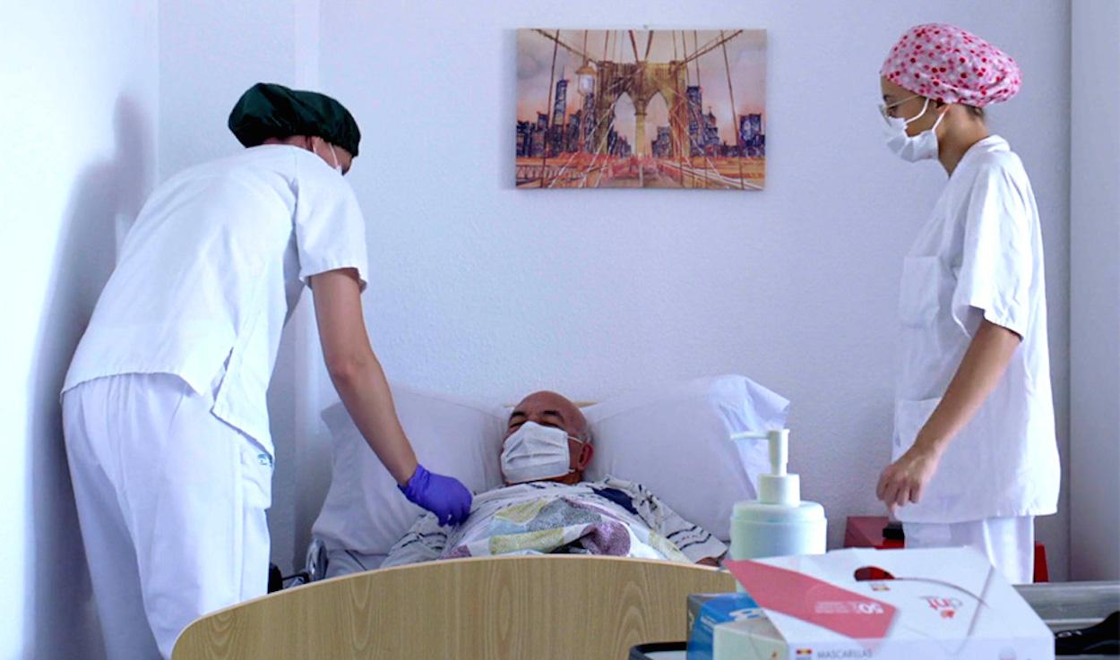 Dos trabajadoras de una residencia de mayores medicalizada atienden a un enfermo. JUNTA DE ANDALUCÍA