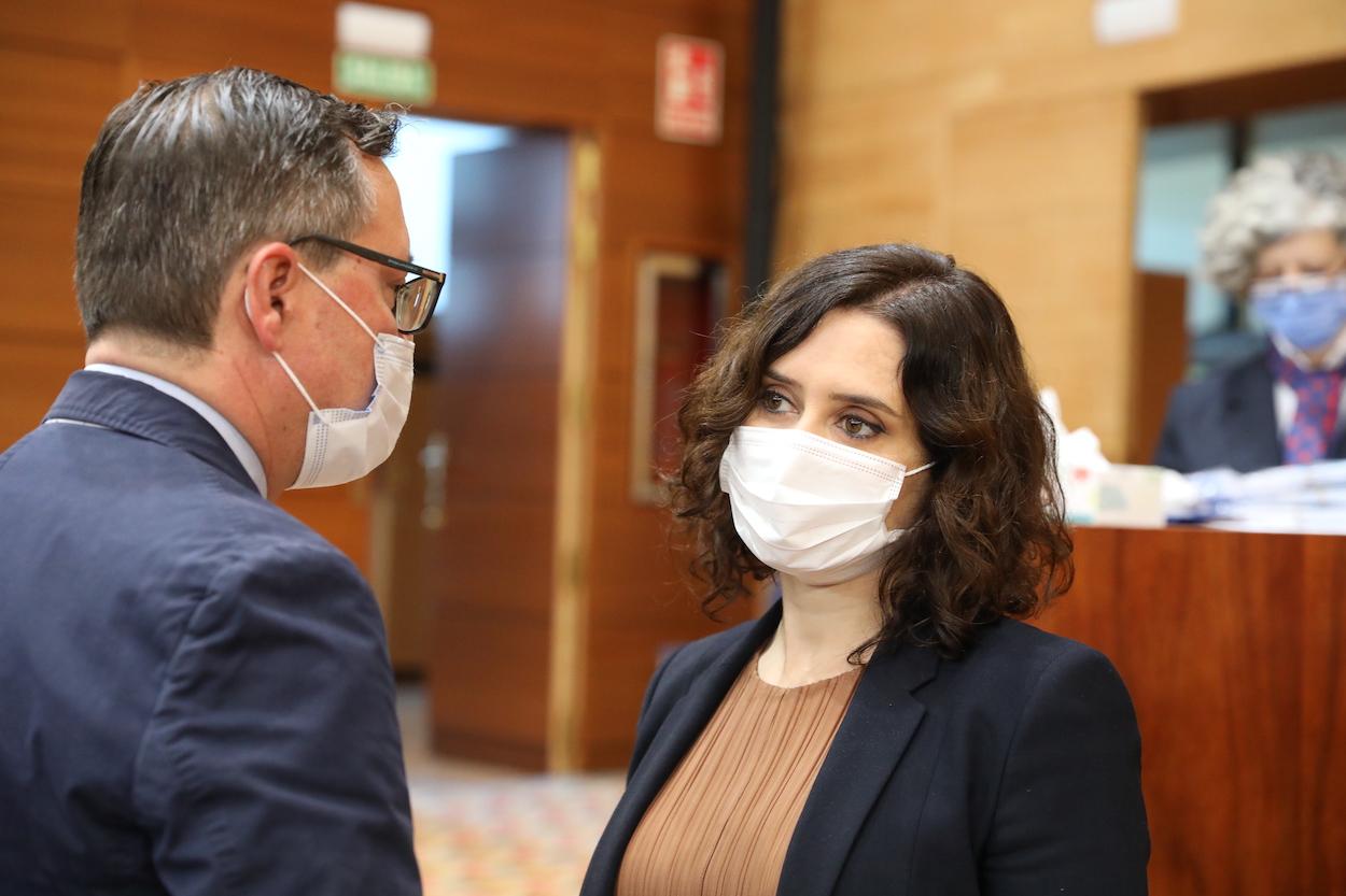 La presidenta de la Comunidad de Madrid, Isabel Díaz Ayuso (d), y el portavoz del PP en la región, Alfonso Serrano (i), durante una sesión plenaria en la Asamblea de Madrid (España)