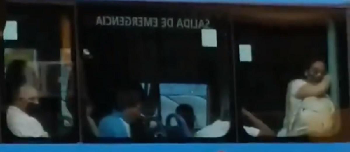 Un hombre limpia el cristal de un bus con su mascarilla y luego se la coloca en la cara