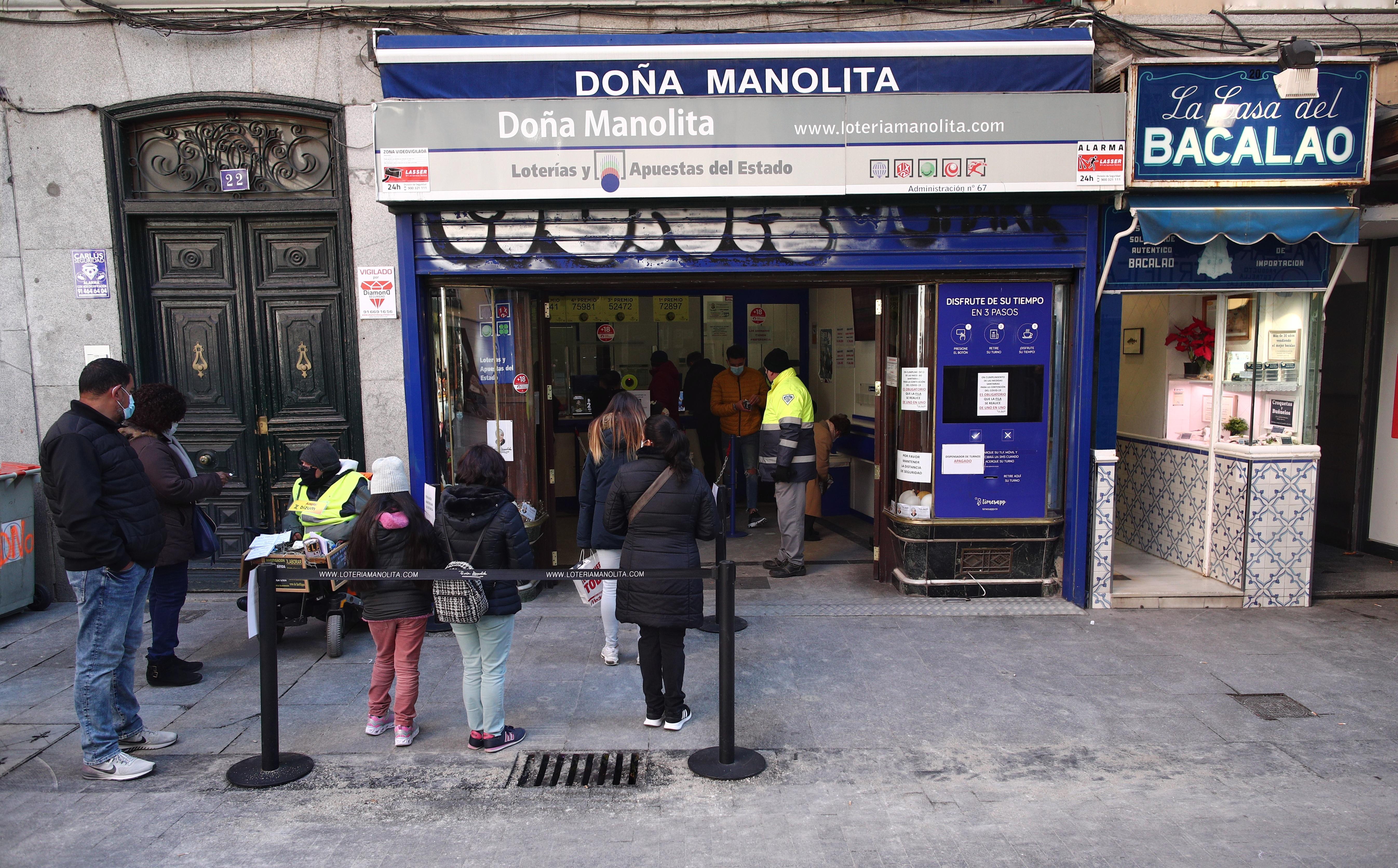 Varias personas hacen cola ante la administración de lotería Doña Manolita, en Madrid (España), a 5 de enero de 2021