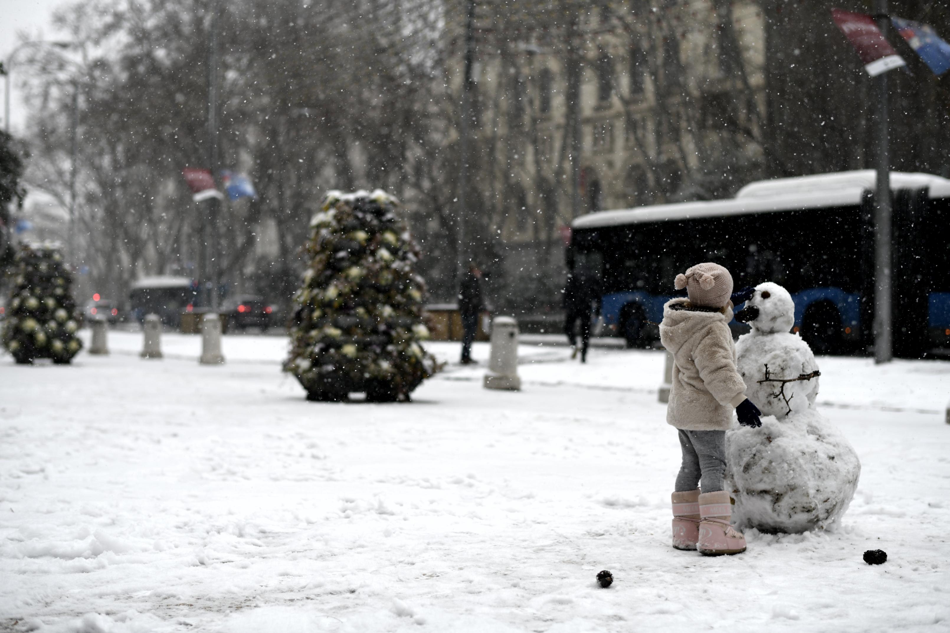 Una niña juega con un muñeco de nieve en la calle en el segundo día de nieve en la capital tras el paso de la borrasca Filomena