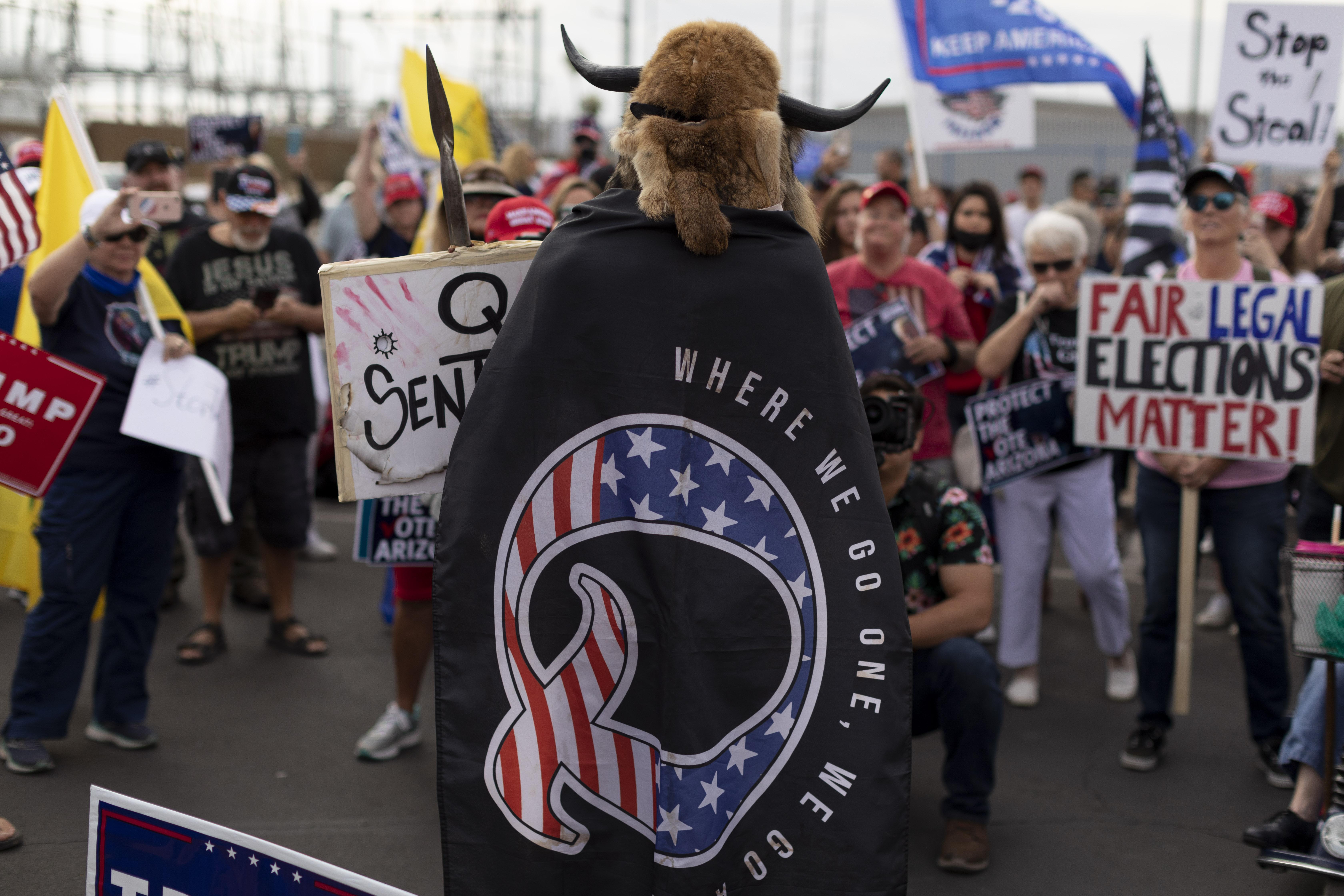 Imagen de recurso de una mujer portando a su espalda una bandera de QAnon.