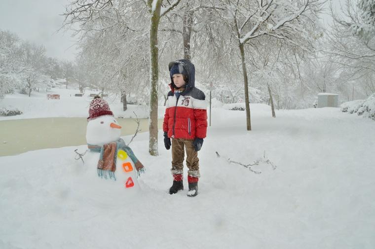 Un niño con un muñeco de nieve.
