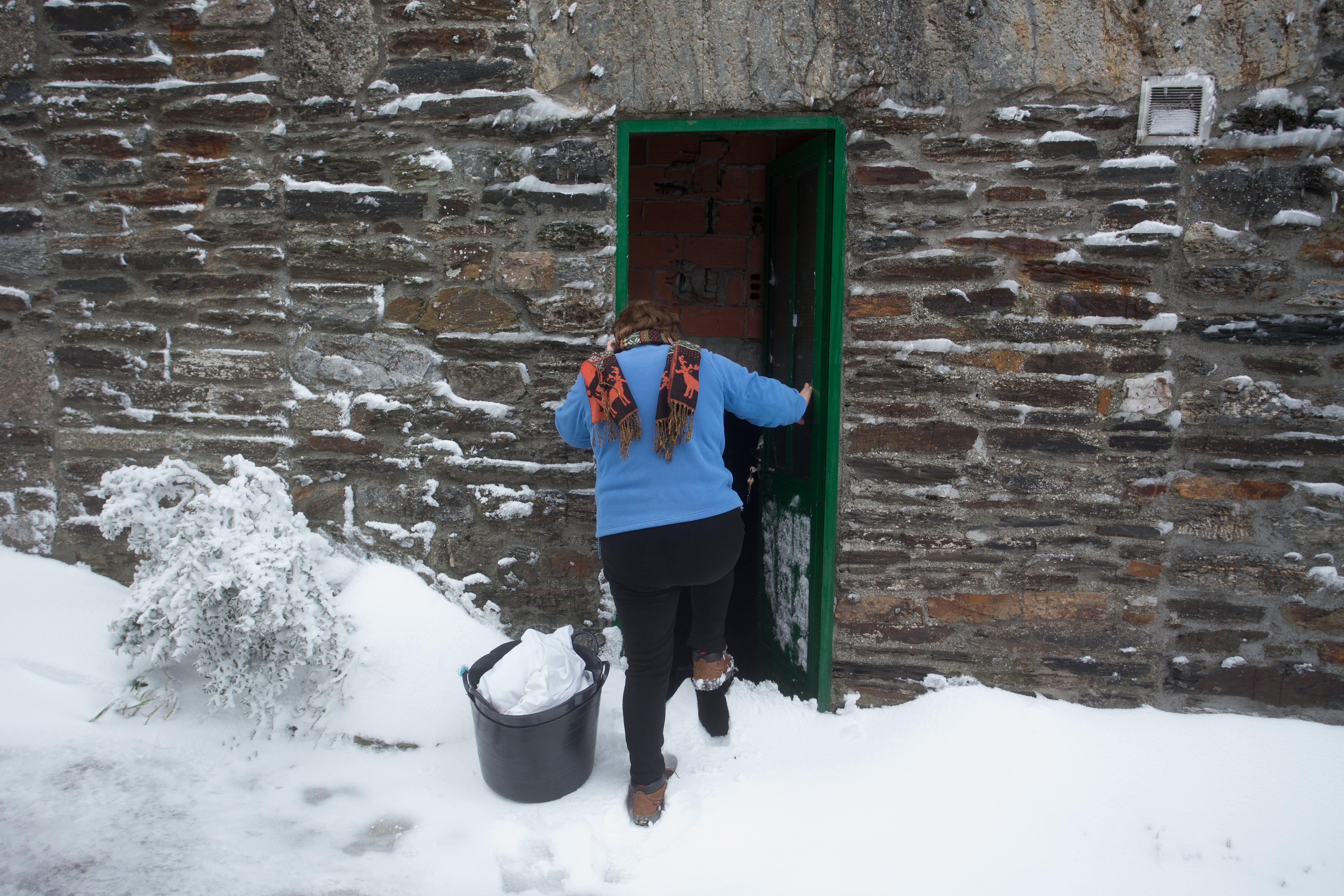 Una vecina en intenta acceder a su vivienda mientras aparta la nieve en Pedrafita do Cebreiro, en Lugo. EP