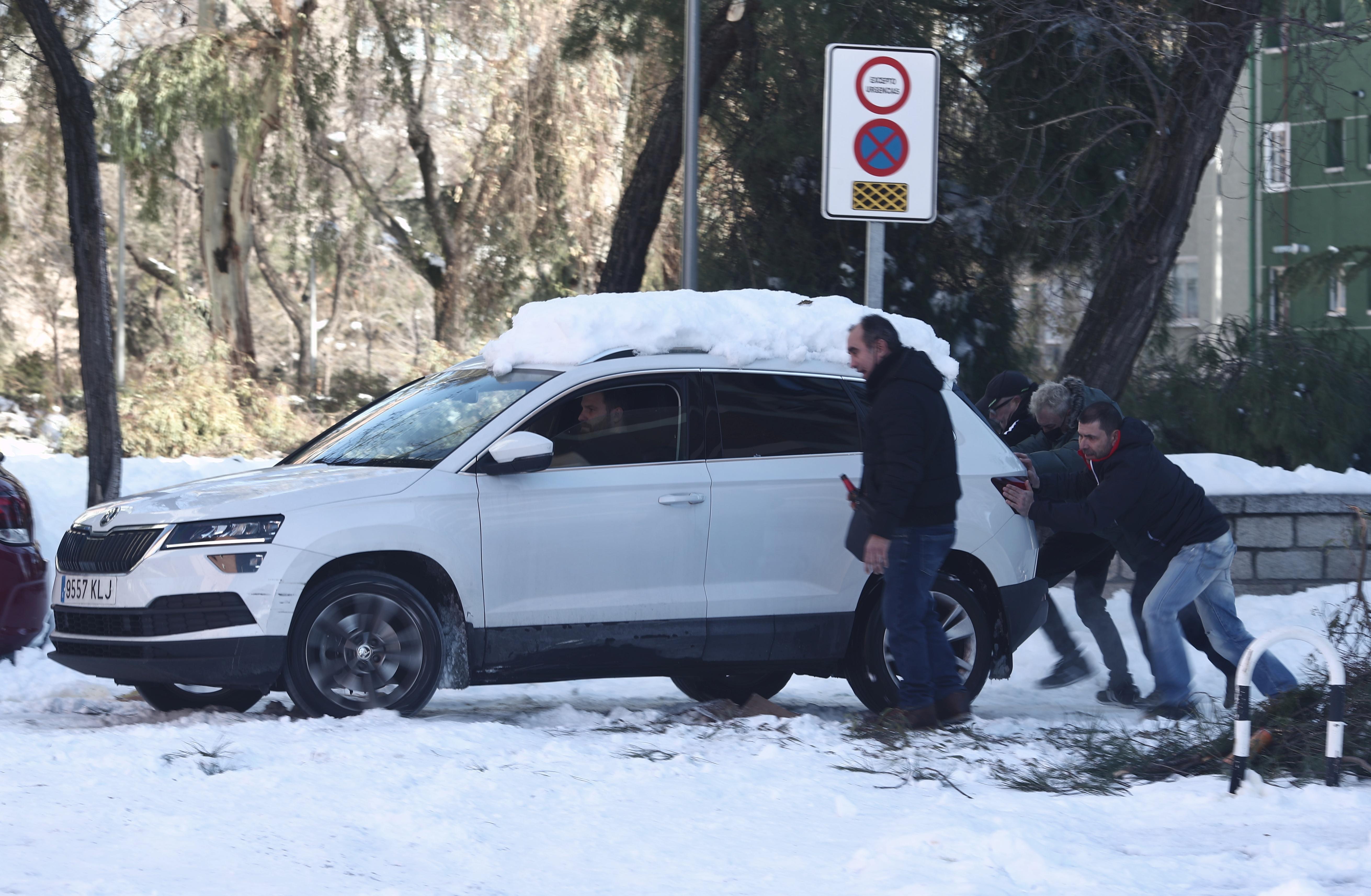 Vecinos del barrio de Pueblo Nuevo, en Madrid, ayudan a un conductor sacar el coche de la nieve. EP