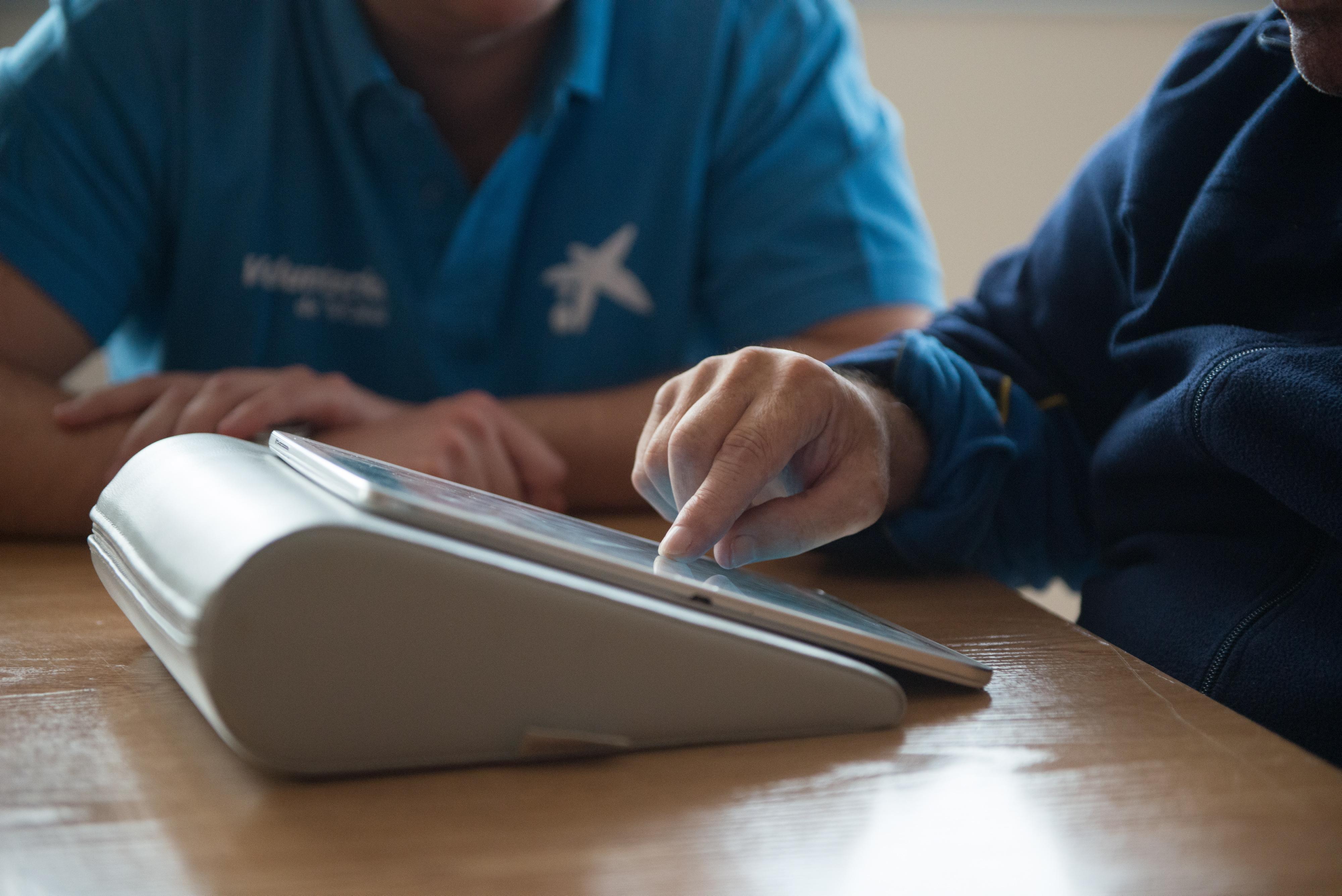Una voluntaria de “la Caixa” forma a una persona en el uso de tablets para comunicarse con sus familiares