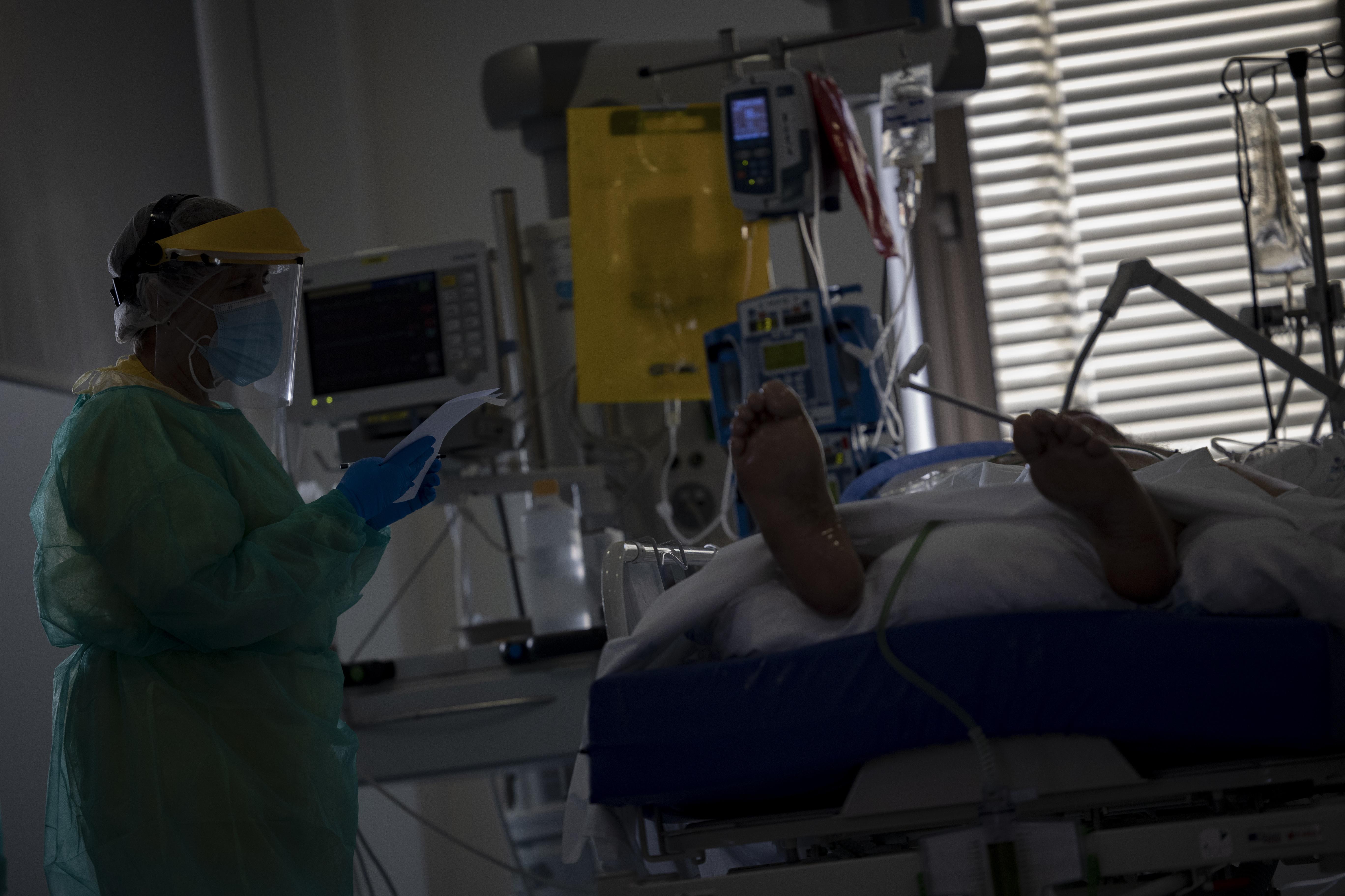 Un sanitario atiende a un paciente en la Unidad de Cuidados Intensivos (UCI) dedicada a enfermos de coronavirus del Hospital Universitario Ramón y Cajal, en Madrid. EP