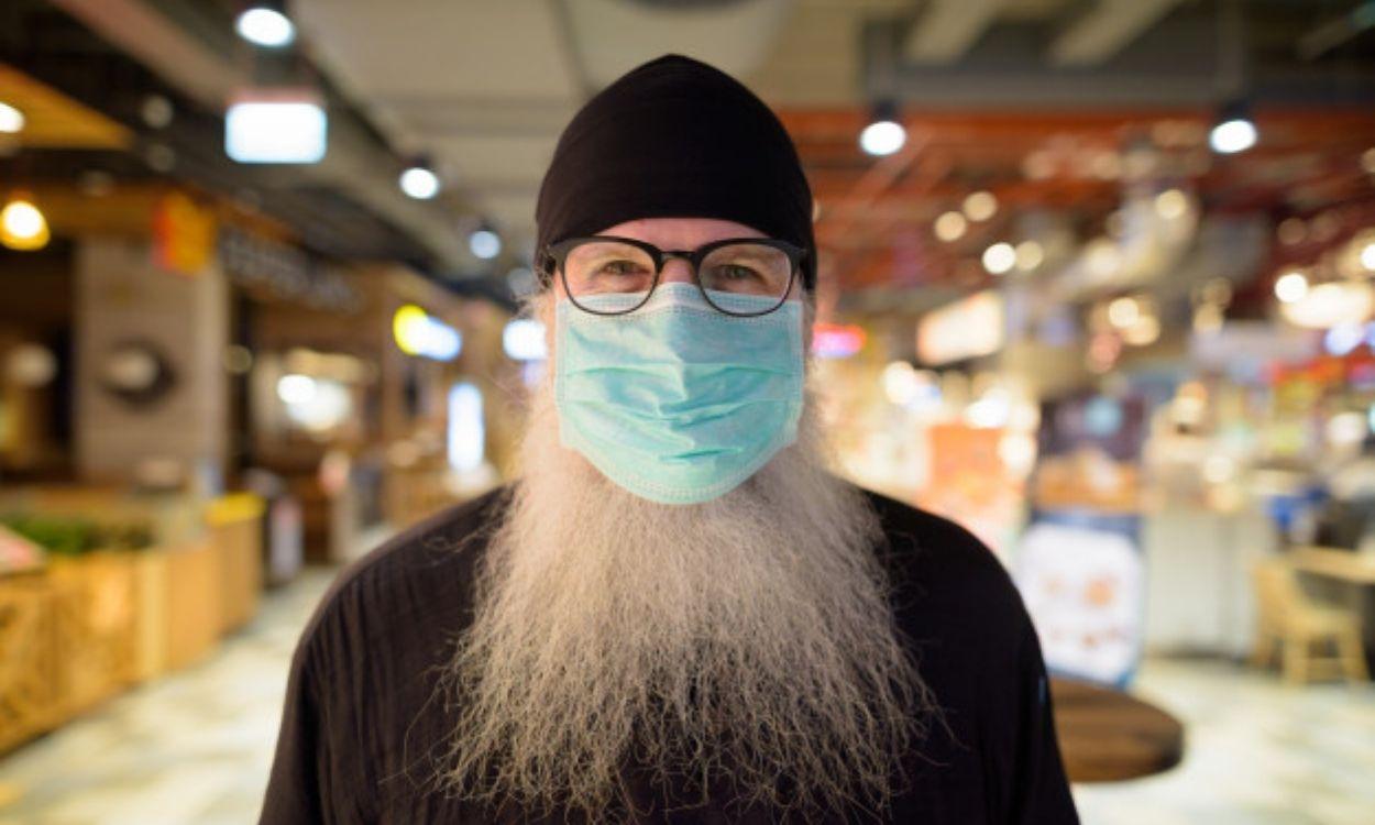 Hombre con una larga barba llevando mascarilla.