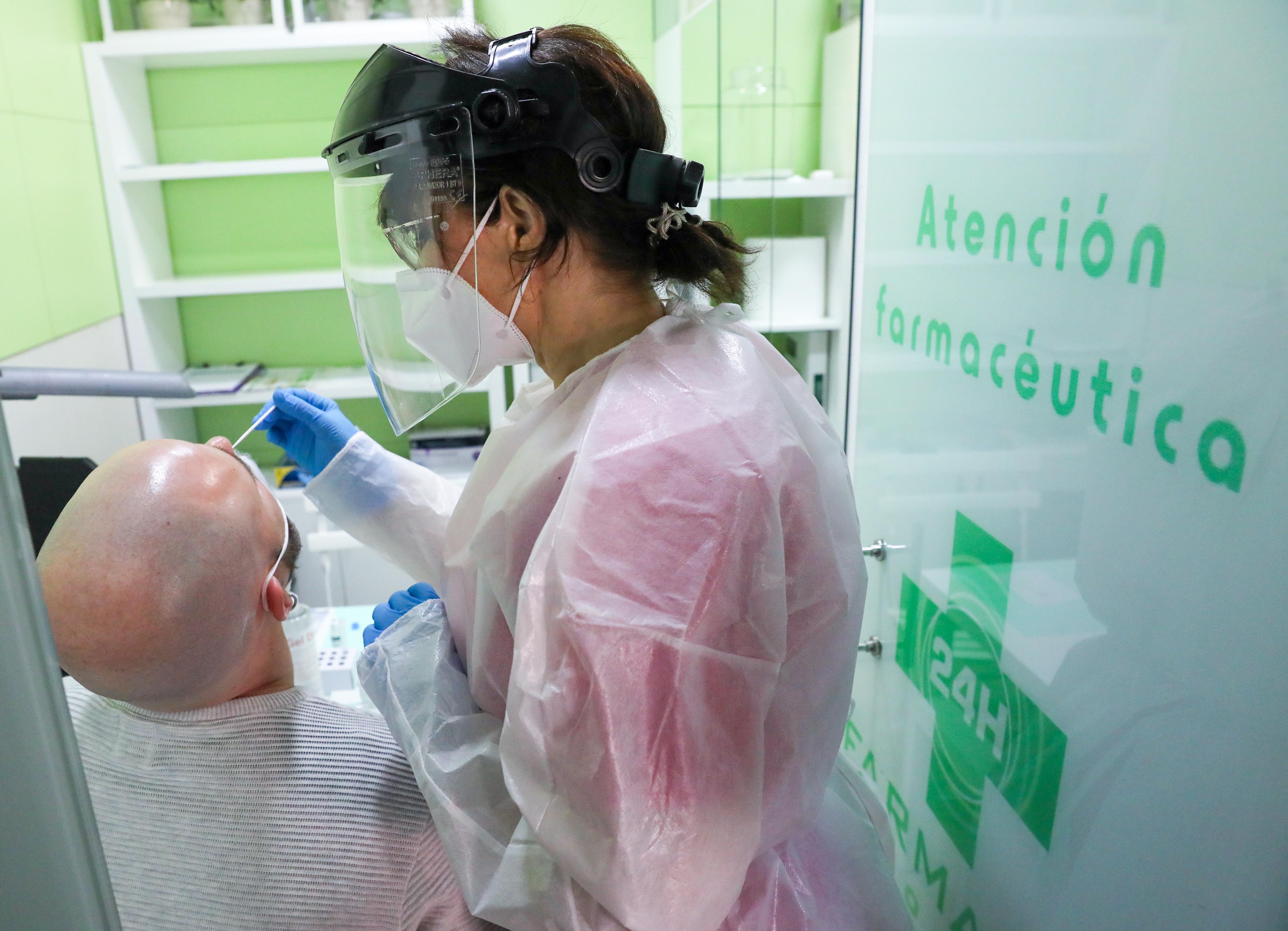 Una farmacéutica realiza un test de antígeno a un hombre en la farmacia. EP