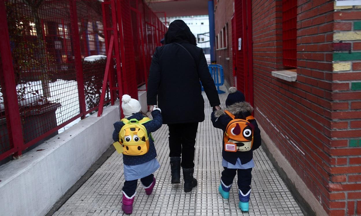 Un familiar lleva de la mano a dos alumnos de un colegio de la Comunidad de Madrid. EP