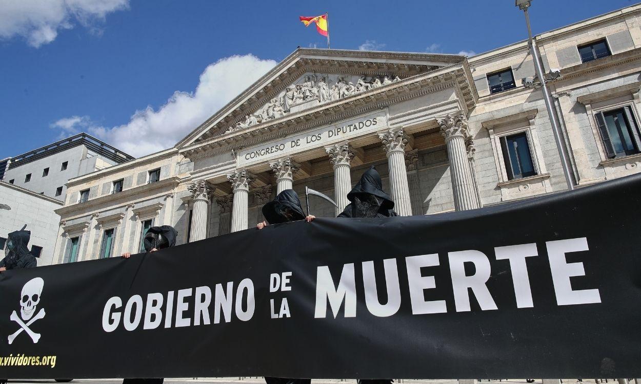 Varias personas disfrazadas de parca sostienen una pancarta donde se puede leer "Gobierno de la muerte" durante una manifestación de Abogados Cristianos a las puertas del Congreso de los Diputados, en Madrid