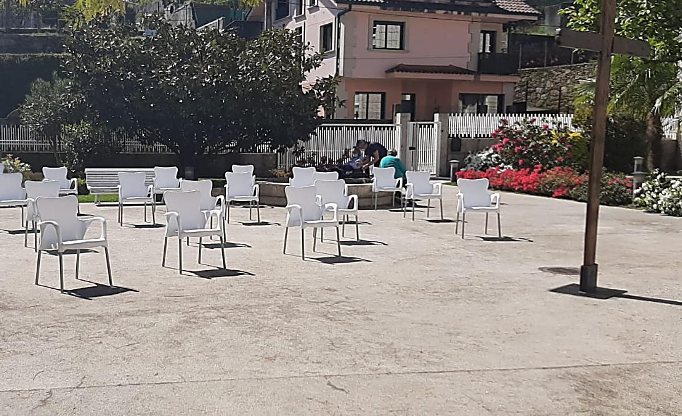 Imagen de las 23 sillas en honor a los 23 fallecidos a causa de la pandemia por el brote de enero en esta residencia, y todo bajo la Cruz de Lampedusa (Foto: REDE).