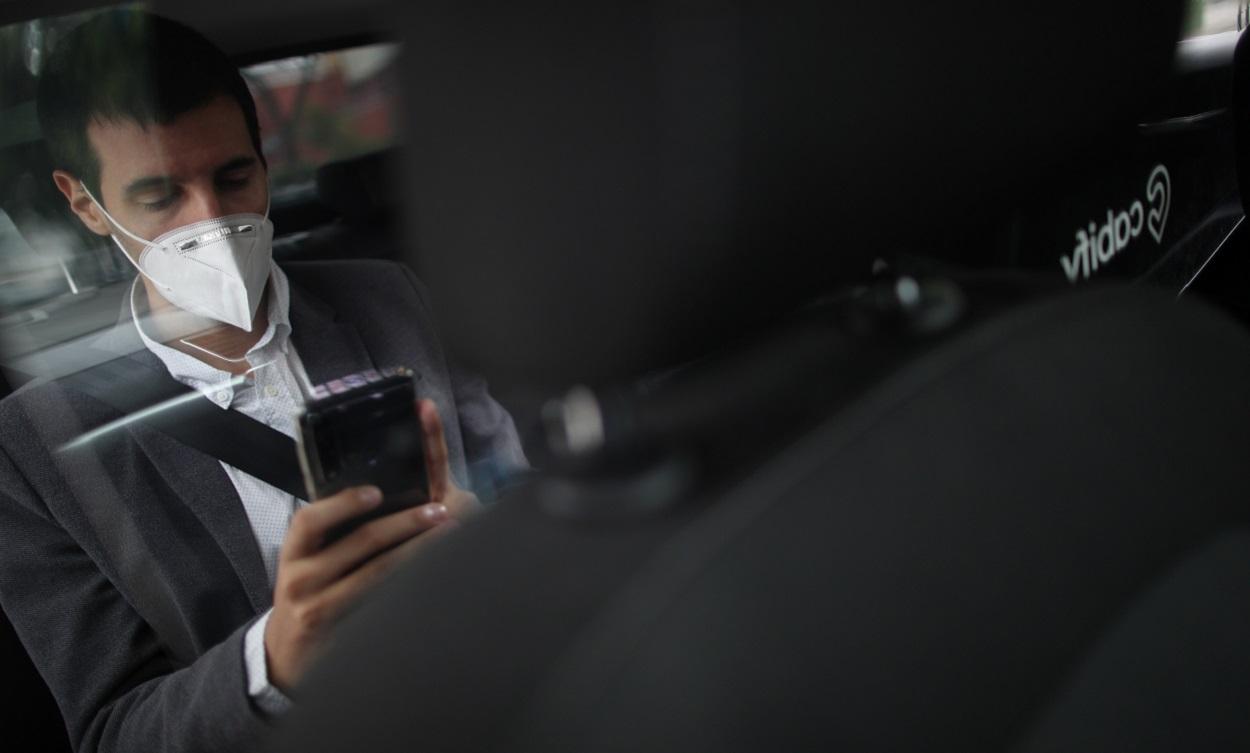 Una persona con una mascarilla en un coche de alquiler. EP