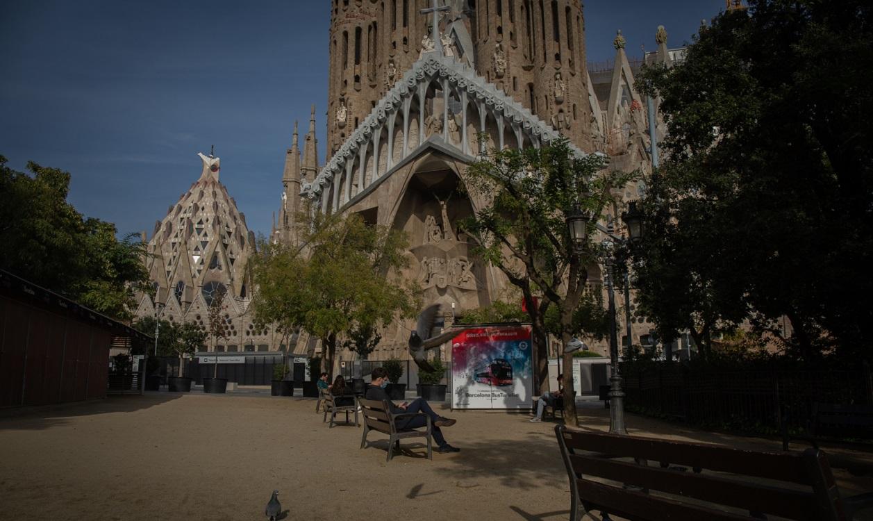 Un hombre sentado en un banco frente a la Sagrada Familia, en Barcelona. EP