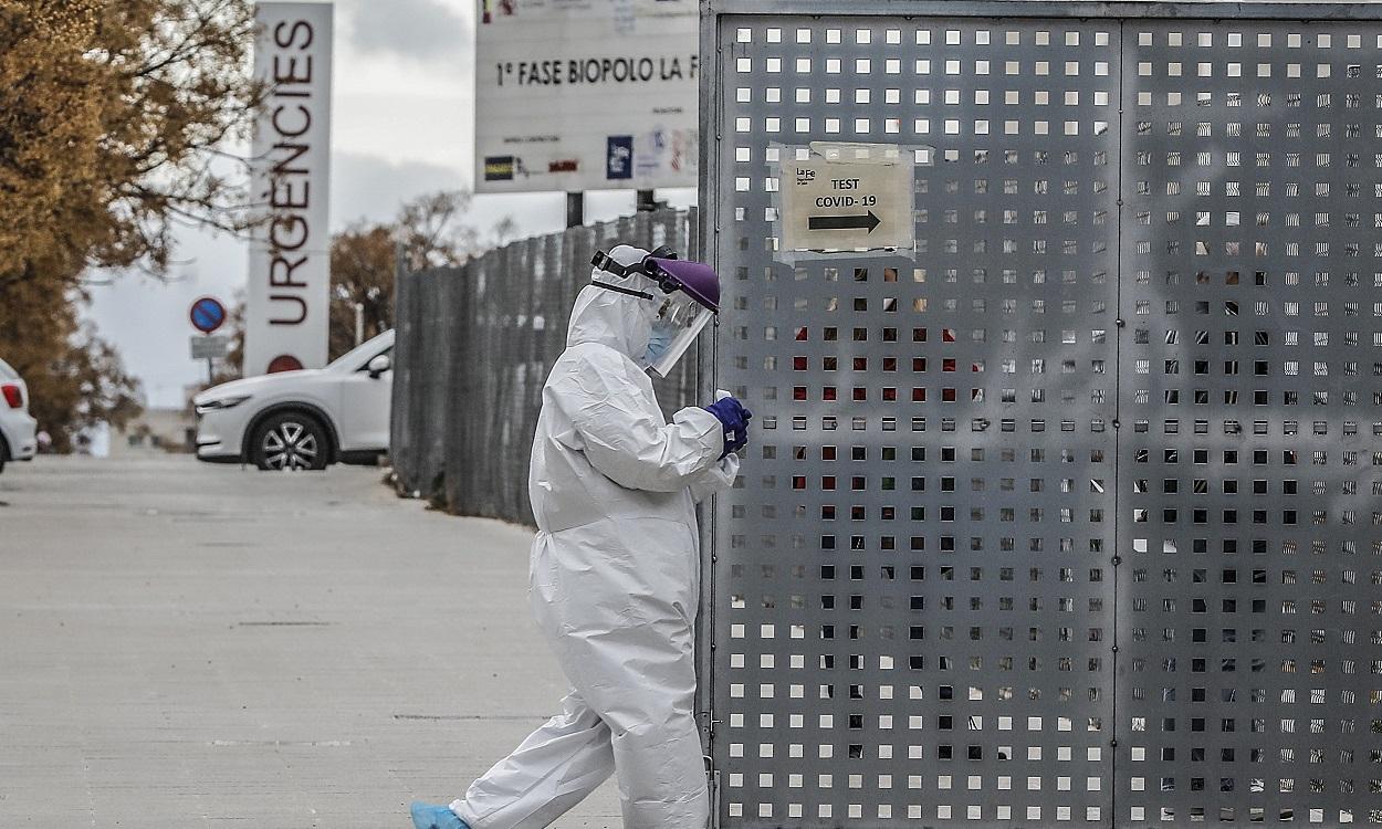 Un sanitario a los alrededores de la fila de vehículos para realizarse una prueba PCR de detección del coronavirus a las puertas del Hospital de Campaña próximo al de La Fe, en Valencia. EP