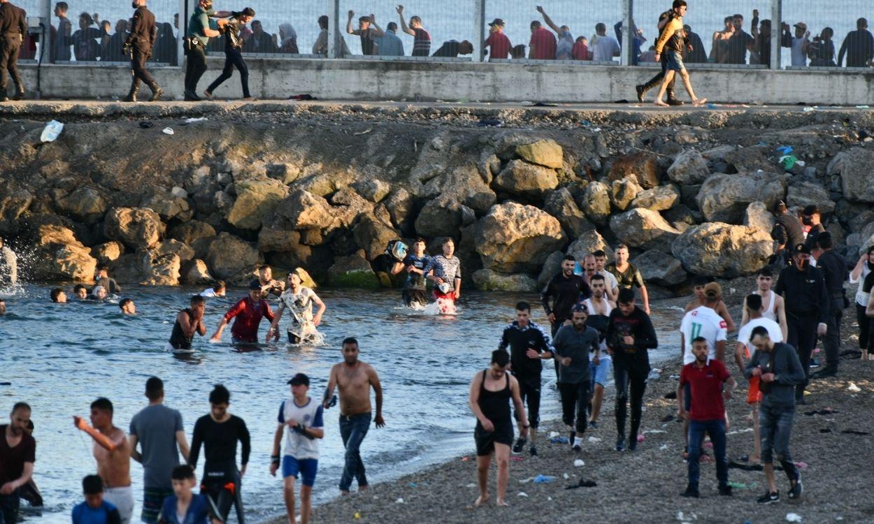 Migrantes marroquíes caminan por la playa del Tarajal (Ceuta). Europa Press.