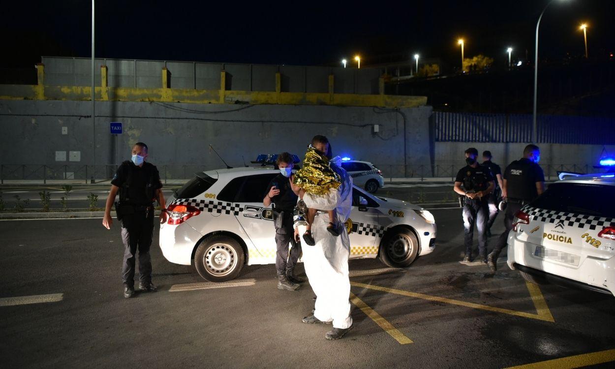 Agentes de Policía junto a un migrante que sujeta a un niño en sus brazos en Ceuta. Europa Press. 