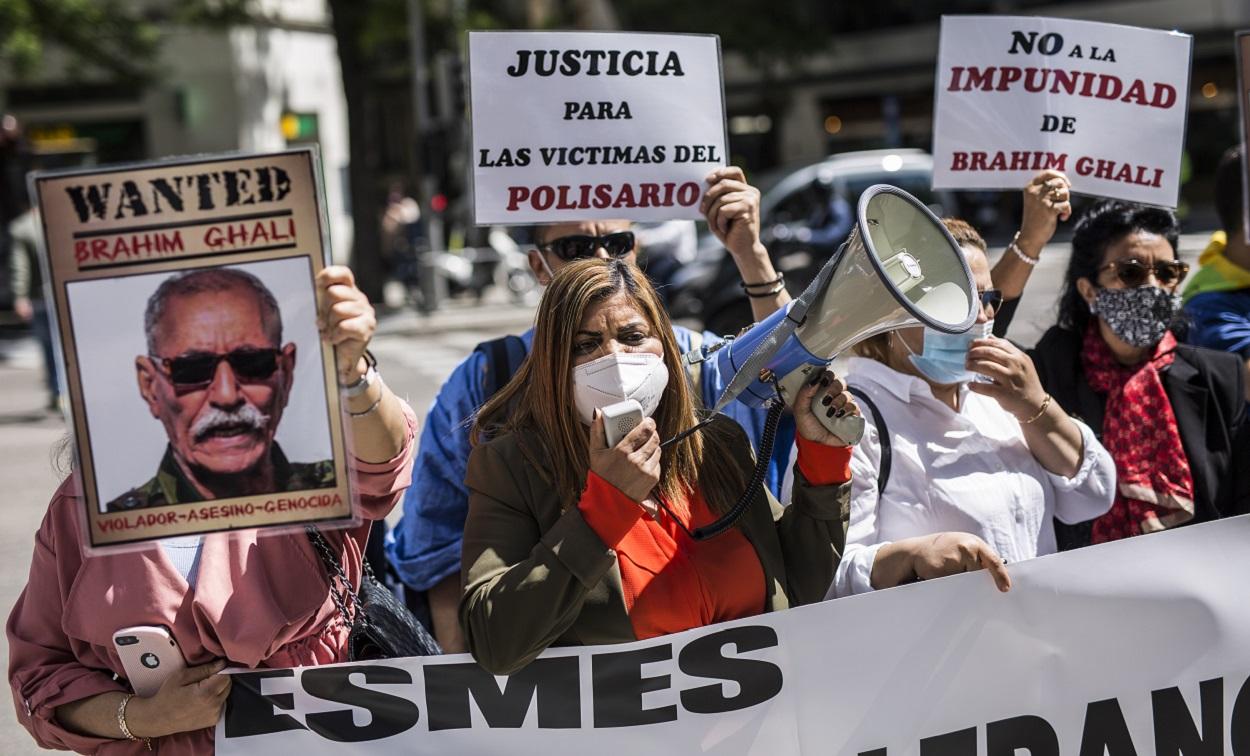 Una mujer con un megáfono, acompañada de varias personas con carteles, protestan contra el líder del Frente Polisario en la puerta de la Audiencia Nacional, a 7 de mayo de 2021. EP