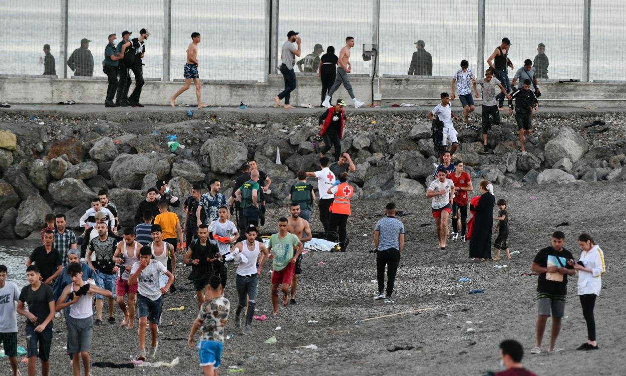 Personas migrantes caminan por la playa del Tarajal. EP