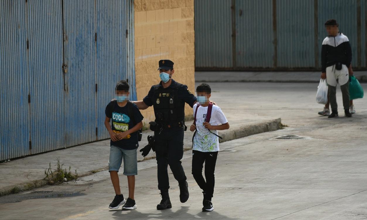 Agentes de la Policía Nacional acompañan a menores marroquíes a las naves acondicionadas anexas a la frontera del Tarajal en Ceuta. EP