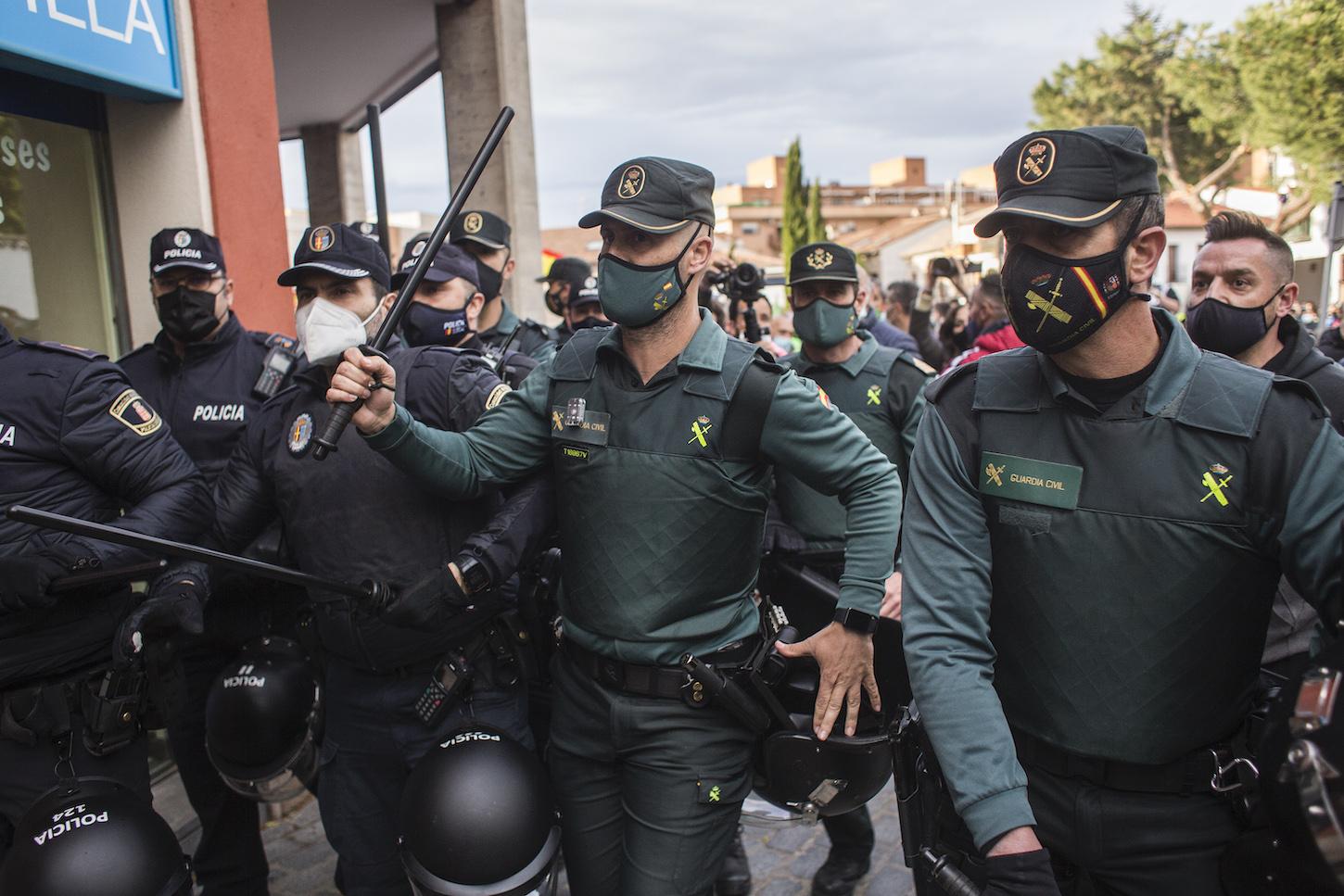 Un grupo de agentes vigila y se protege durante un mitin de Vox, a 21 de abril de 2021, en Navalcarnero, Madrid (España). EP