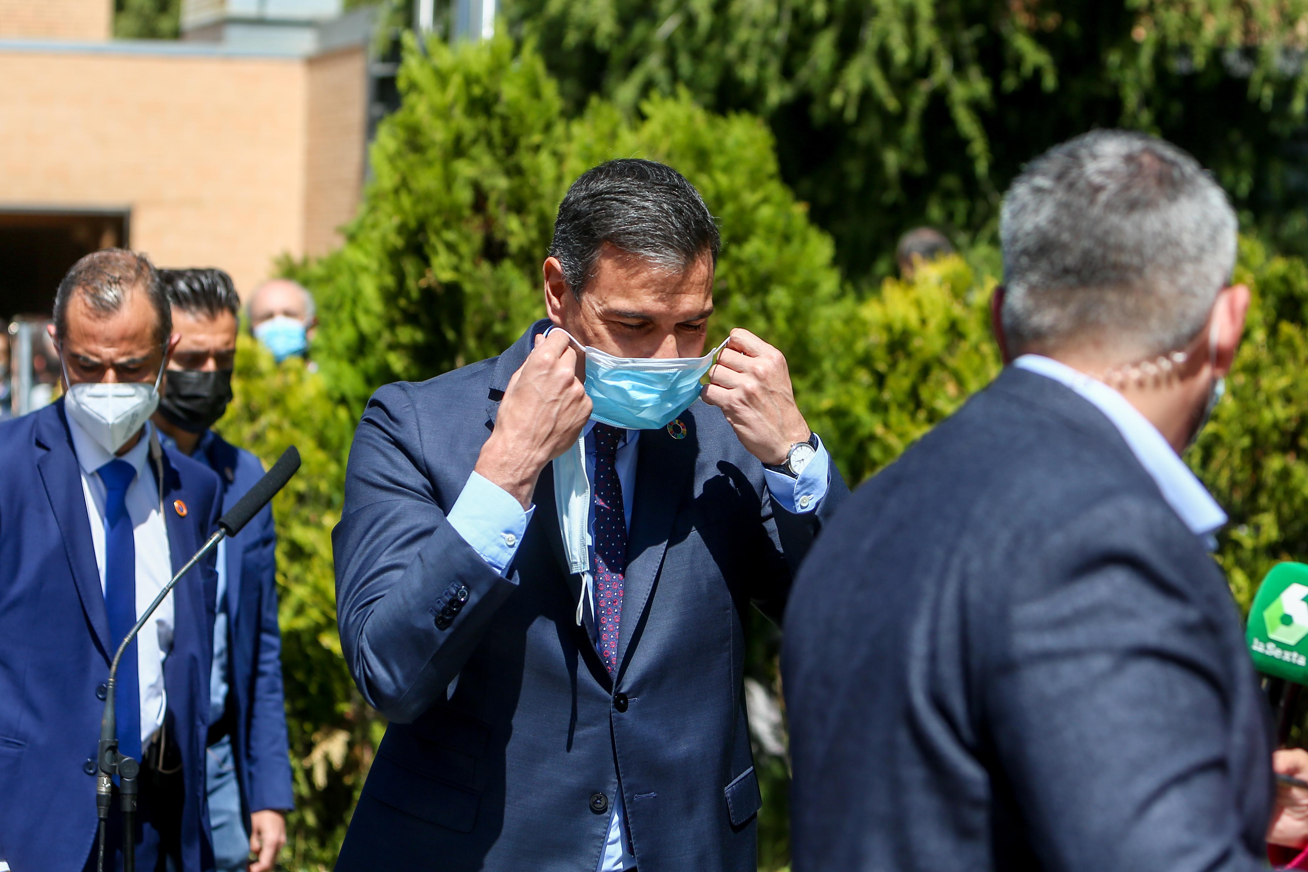 El secretario general del PSOE y presidente del Gobierno, Pedro Sánchez (c) se pone una doble mascarilla a su llegada al Centro Cultural Volturno para ejercer su derecho a voto, a 4 de mayo de 2021, en Pozuelo de Alarcón, Madrid (España). 