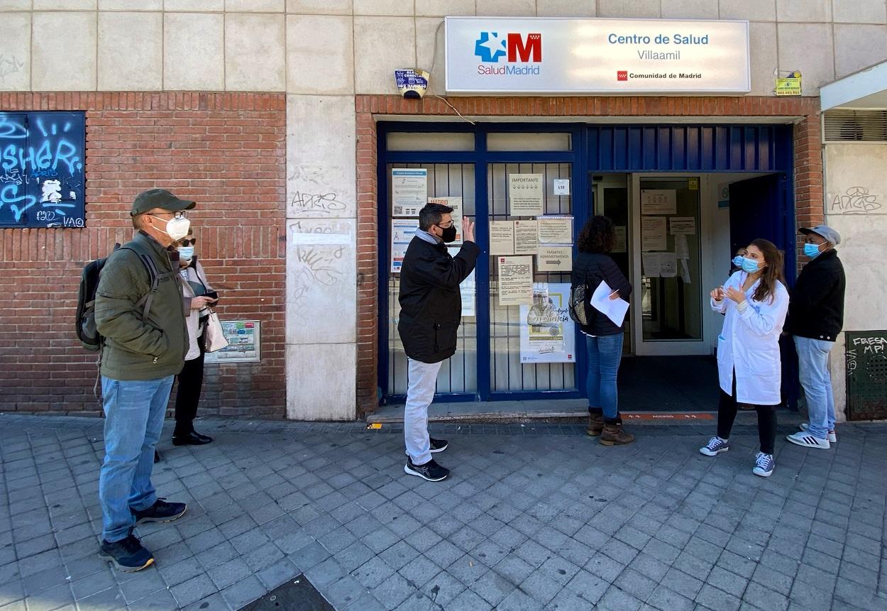 Una trabajadora habla con un hombre delante del Centro de Salud Villaamil, delante del cual varias personas esperan a ser atenidas. Eduardo Parra / Europa Press