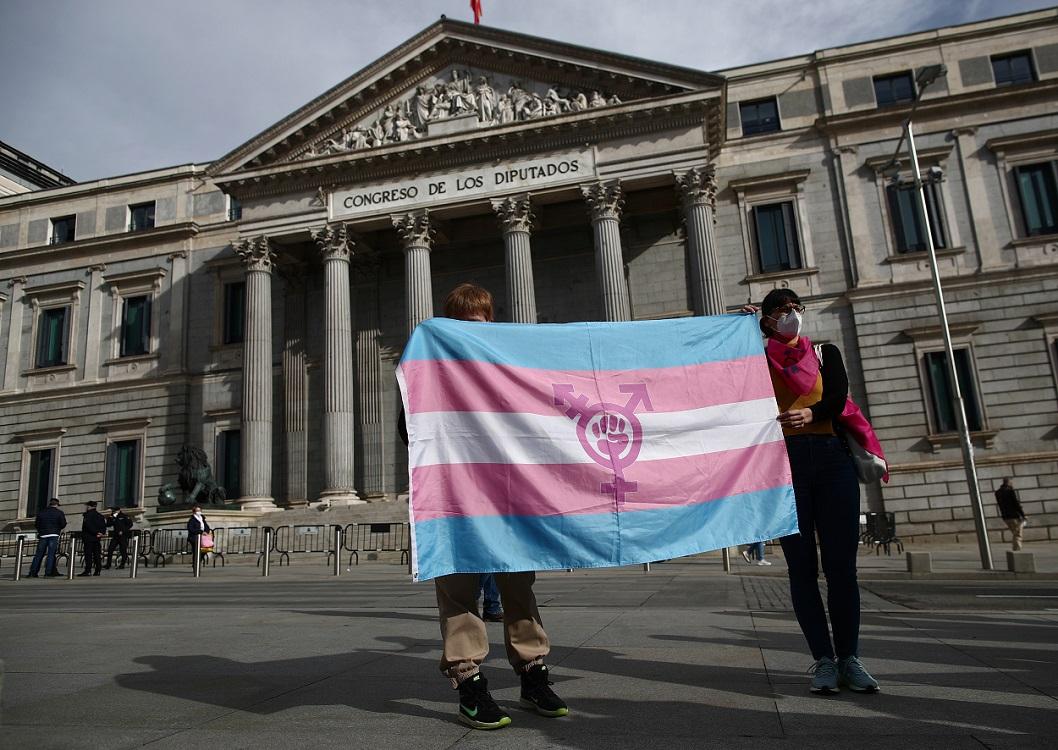Dos personas sujetan la bandera transexual en la puerta del Congreso. EP