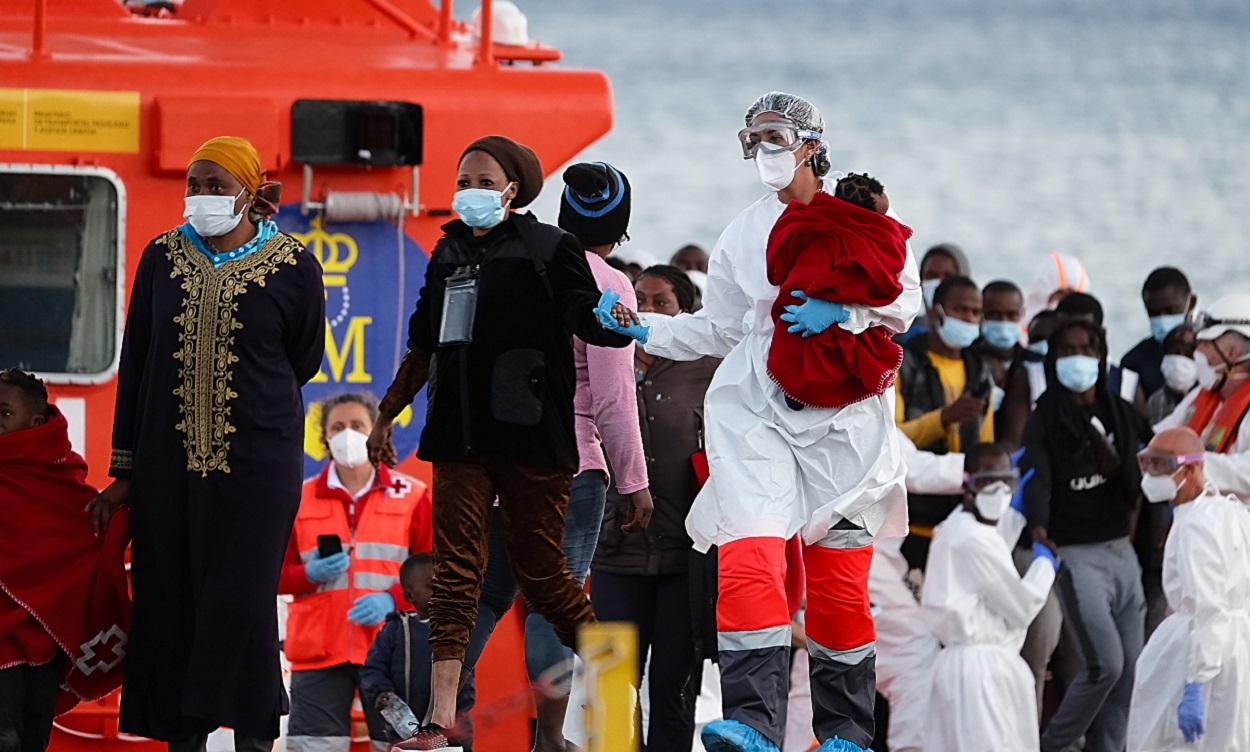 Una sanitaria lleva en brazos a una niña que llega a tierra junto con otros migrantes en Canarias. EP archivo