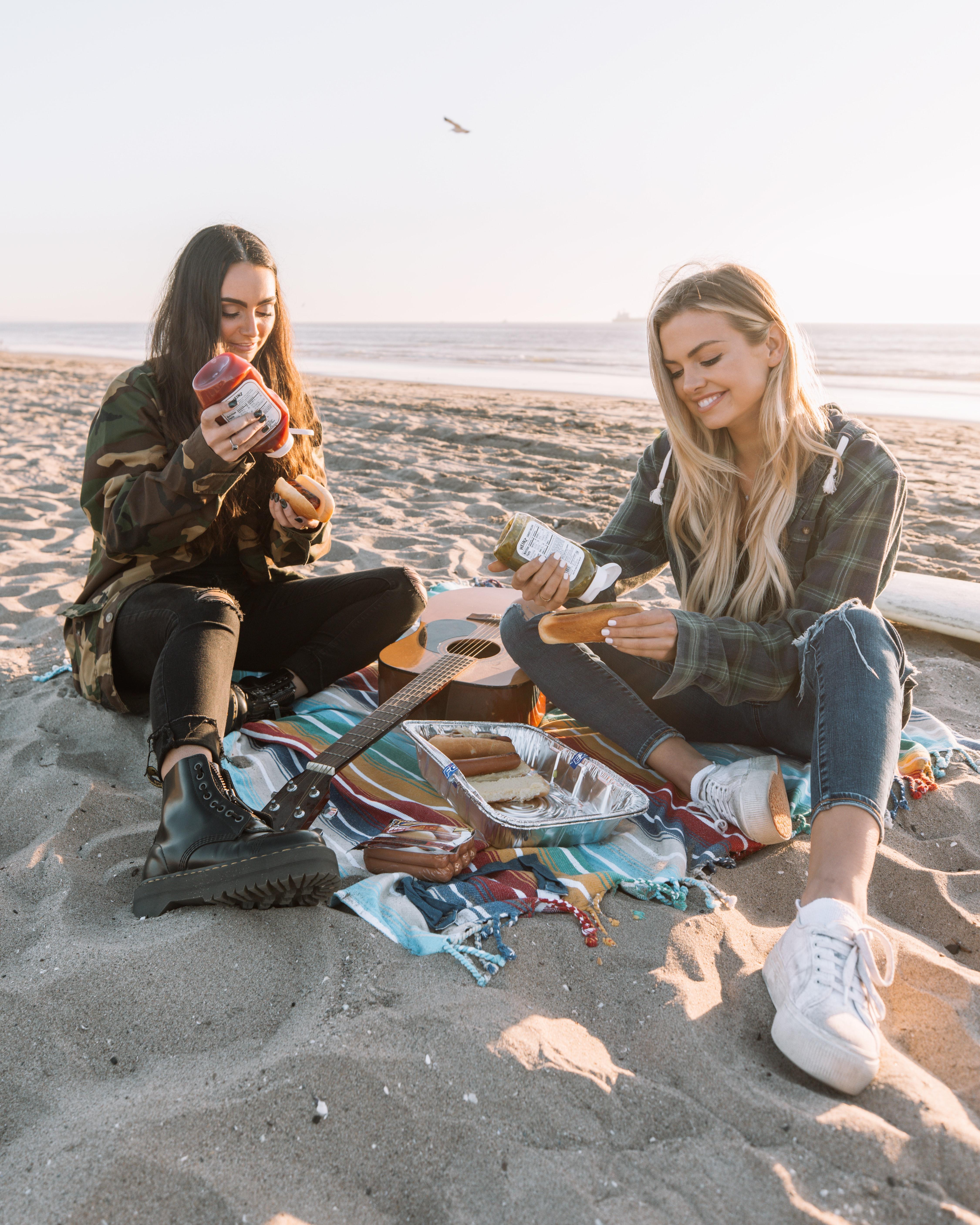 Dos jóvenes comiendo carne en la playa. Unsplash