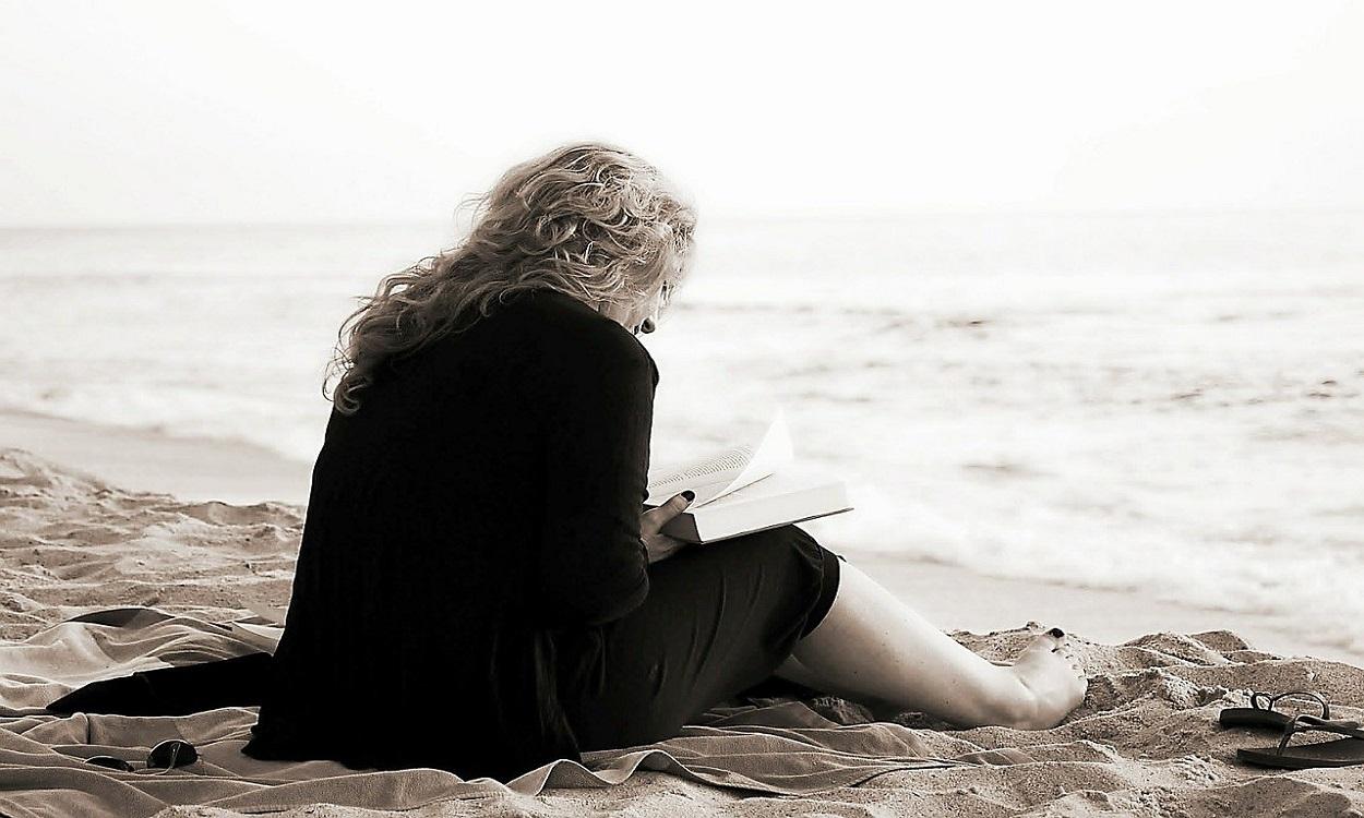 Una mujer leyendo en la playa. Pixabay