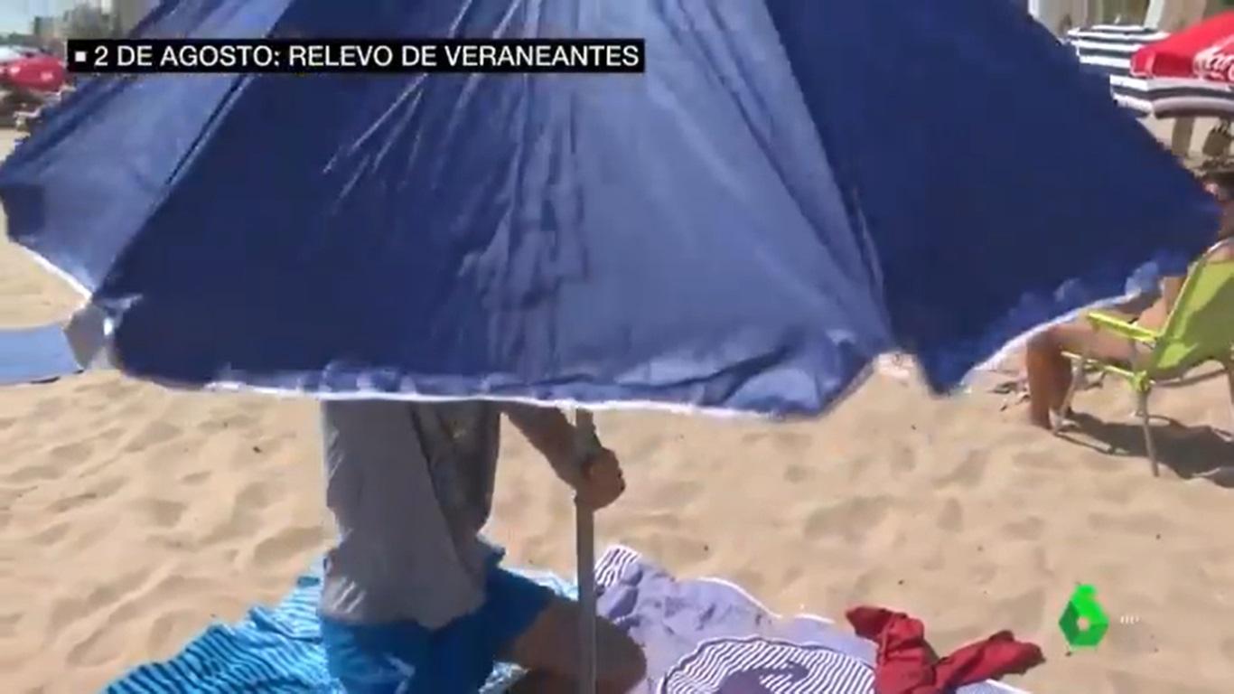 Un hombre intenta abrir una sombrilla en la playa de Gandía. laSexta.