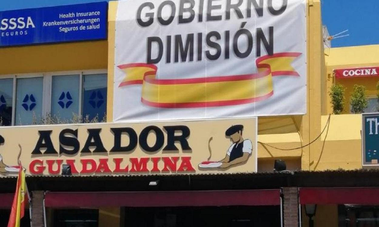 Cartel de "Gobierno Dimisión" en la fachada del Asador Guadalmina.