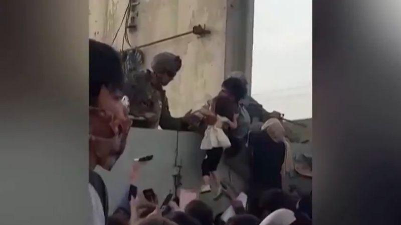 Imagen viral de una niña afgana aupada y recogida por soldados estadounidenses en Kabul.