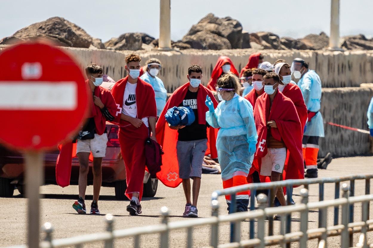 Una trabajadora de la Cruz Roja con varios de los 34 migrantes que han sido rescatados por Salvamento Marítimo cuando iban en una patera.