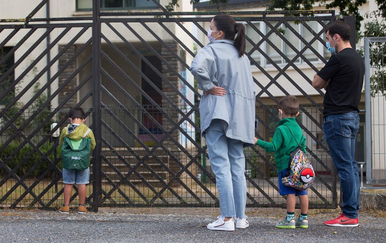 Imagen de padres llevando a sus hijos al colegio con mascarilla. EP