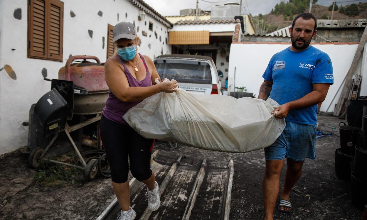 Dos personas sacan cosas de sus casas antes de ser desalojados a causa del volcán de La Palma. EP