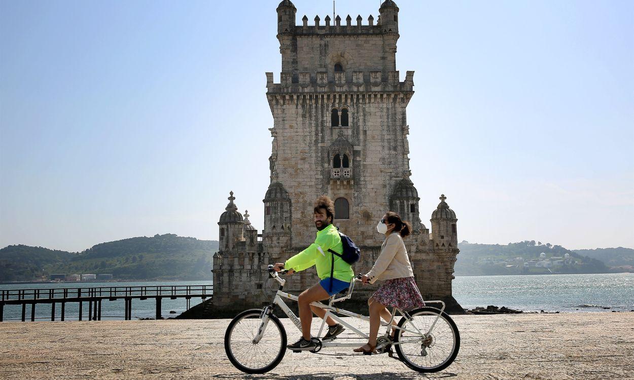 Dos personas montan en bicicleta en la Torre de Belén en Lisboa, Portugal. EP