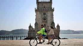 Dos personas montan en bicicleta en la Torre de Belén en Lisboa, Portugal. EP
