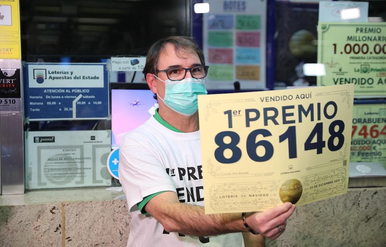 Un empleado de la administración de Puerta de Atocha con el cartel que anuncia haber vendido El Gordo